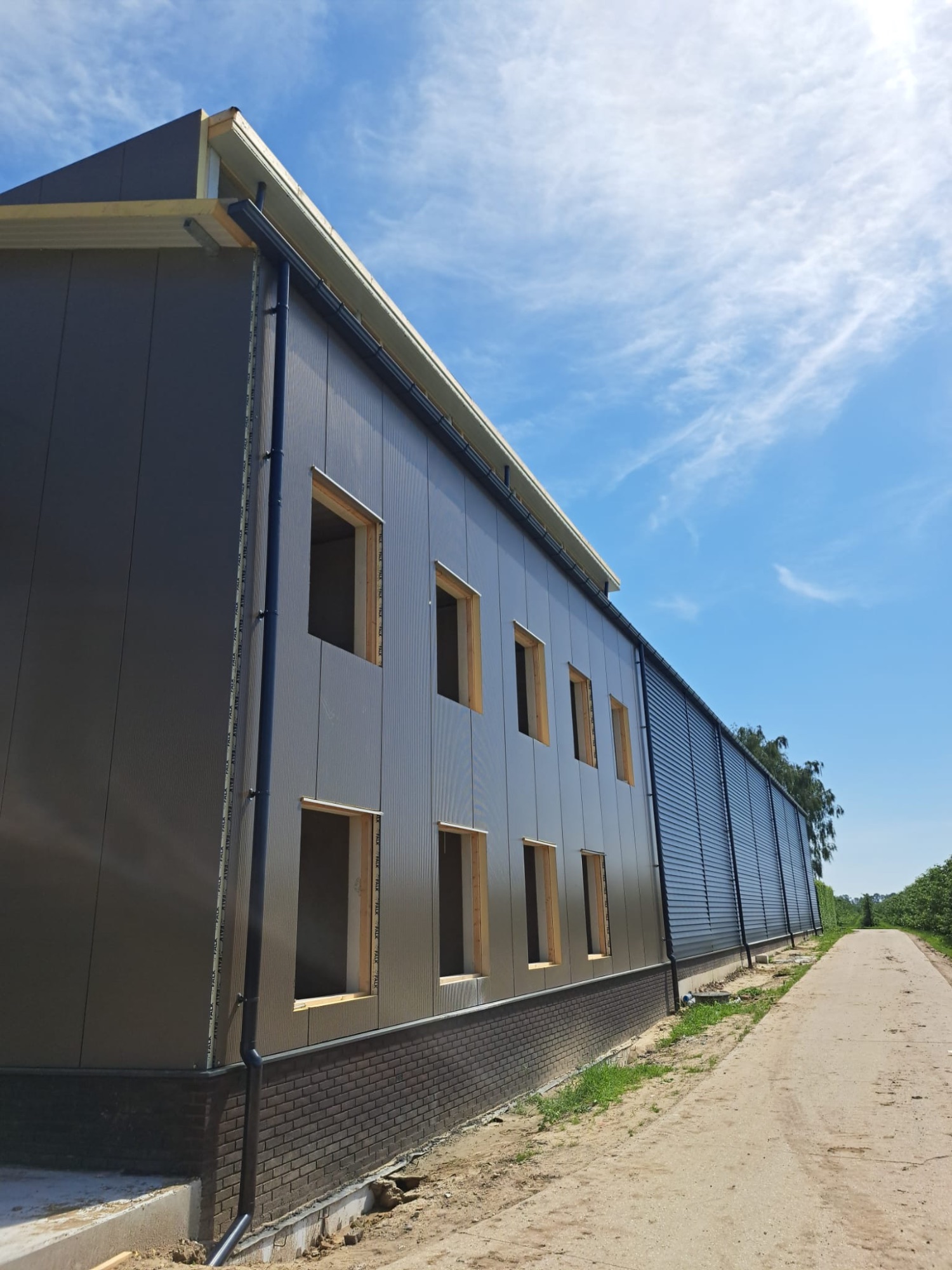 Aluminium dakgoot en hemelwaterafvoeren op een antracieten bedrijfshal