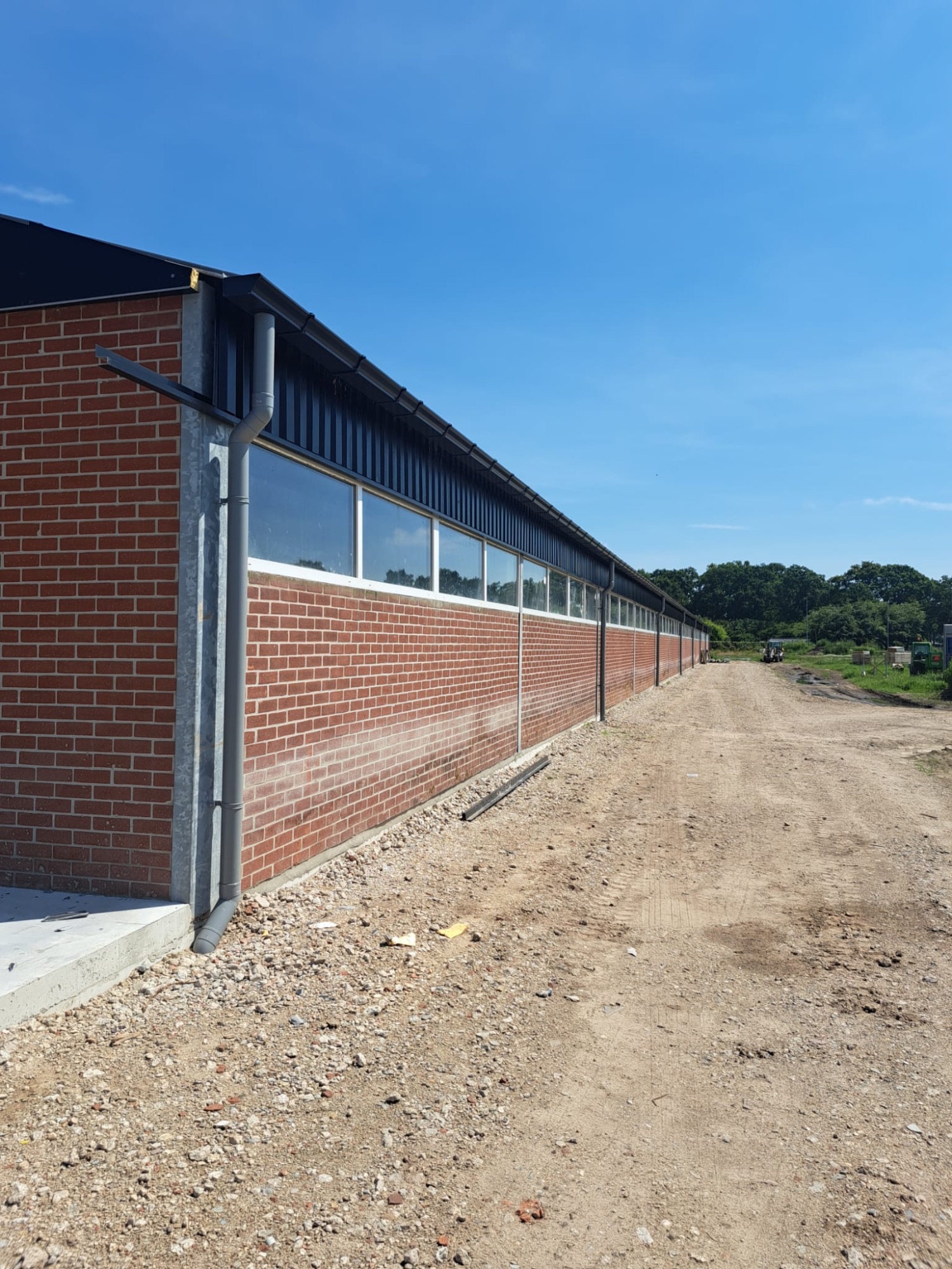 Aluminium dakgoot op een stal met rood metselwerk en lichtstraat